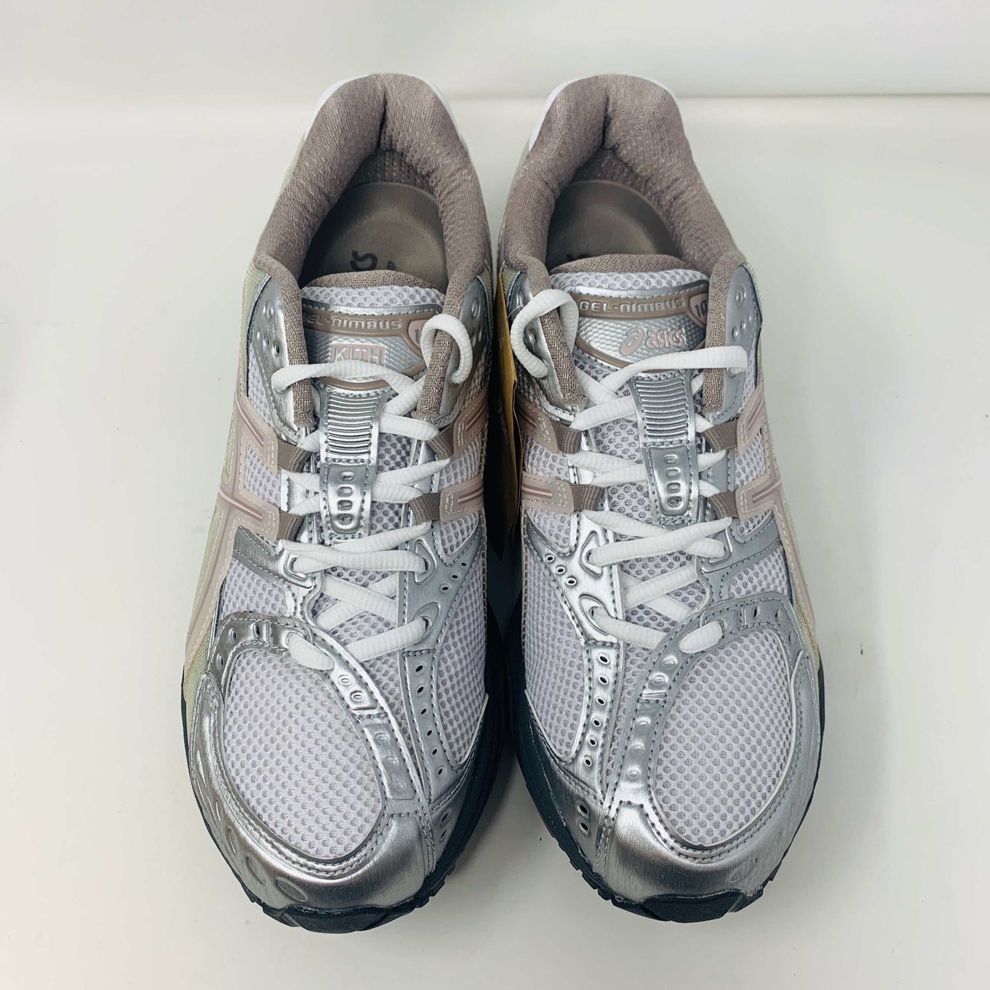 The ASICS Gel-Nimbus 10.1 Kith White Morganite features white, gray, and light pink tones displayed on a shoebox. Includes two sets of laces: one brand new in white with black specks and one plain beige, sealed in plastic bags, ready for 2024.