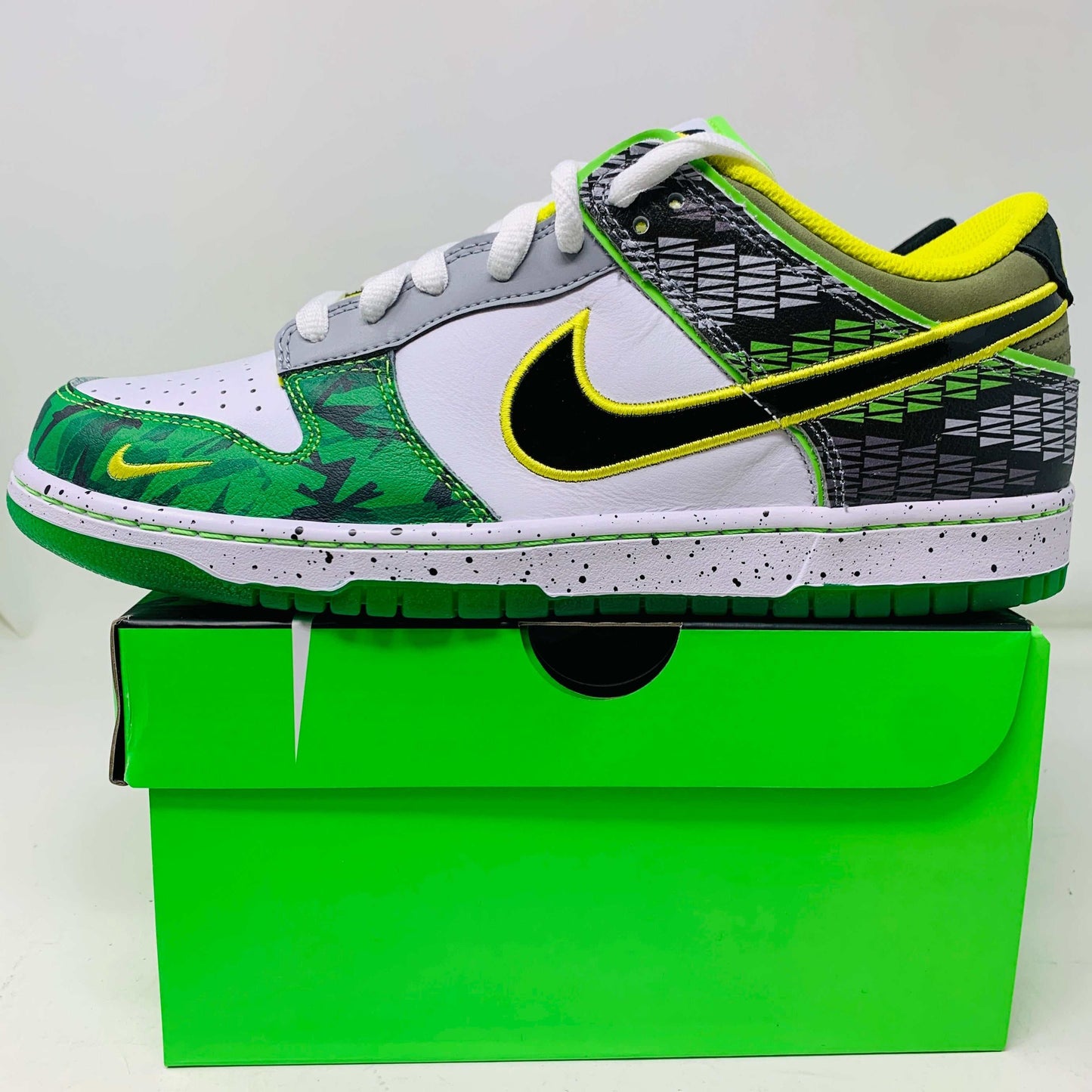 Nike Dunk Low What the Duck Away University of Oregon PE sneaker, brand new with extra laces and keychain, displayed on a green box.