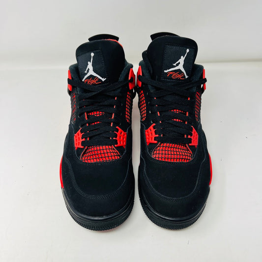 The Jordan 4 Retro Red Thunder sneakers come in an excellent condition shoebox, showcasing clean black uppers with bold red accents on the midsole, eyelets, and mesh. The box features the iconic Air Jordan logo and a shoe information label.