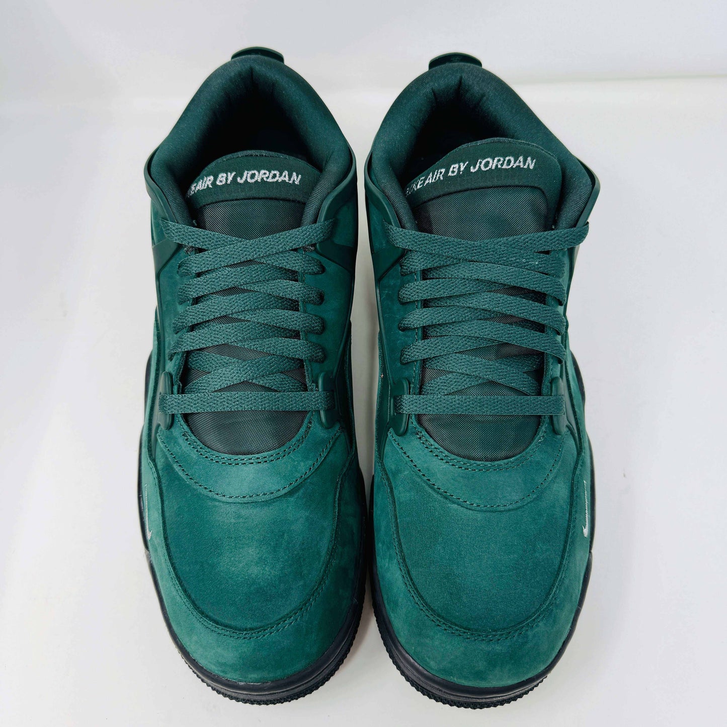 The Jordan 4 RM SP Nigel Sylvester Grandmas Driveway sneakers feature a dark green color with Air by Jordan on the tongue in white, accented with white laces and a low-top design, all set against a plain white background.