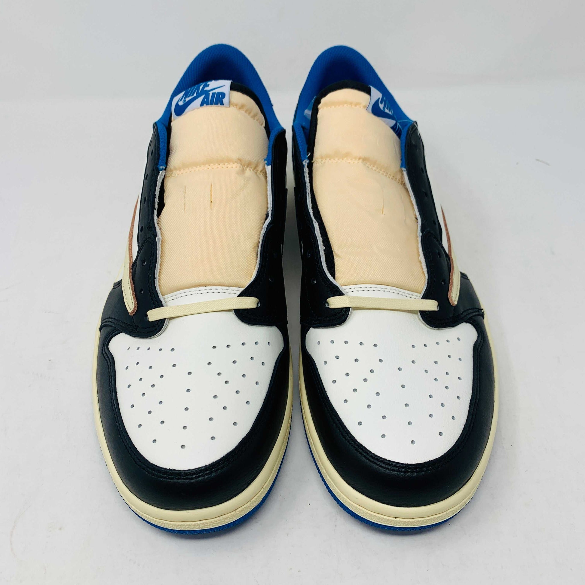 The Jordan 1 Low Travis Scott x Fragment sneakers feature a black and white leather upper with blue accents, a unique beige backward swoosh, and come in a branded Nike box with graphics. These brand-new shoes include an extra set of laces for added versatility.
