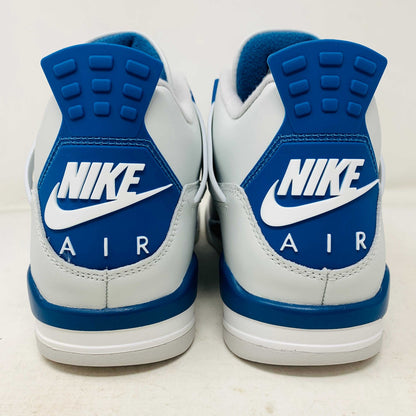 The Jordan 4 Retro Military Blue (2024) sneaker, with white and blue mesh details and a visible air cushion, rests on a black speckled NIKE AIR box with bold orange text. It is 100% authentic, including orange tags, ensuring it’s brand new.