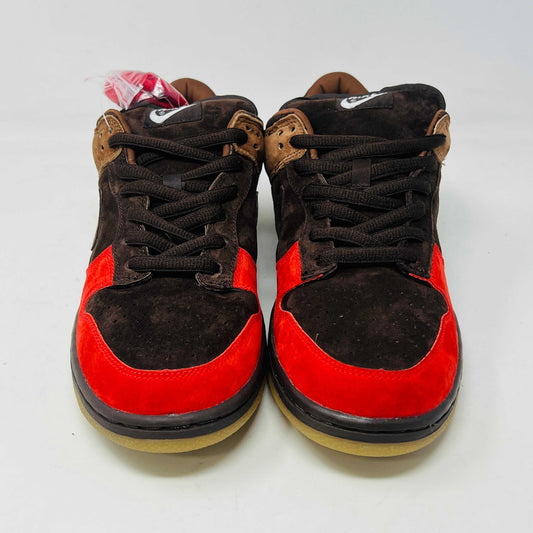 A pair of BRAND NEW Nike SB Dunk Low Bison sneakers featuring brown and red suede uppers, black laces, EXTRA LACES included, and a light brown sole. Positioned side by side on a white background, they promise to be 100% authentic and stylish.