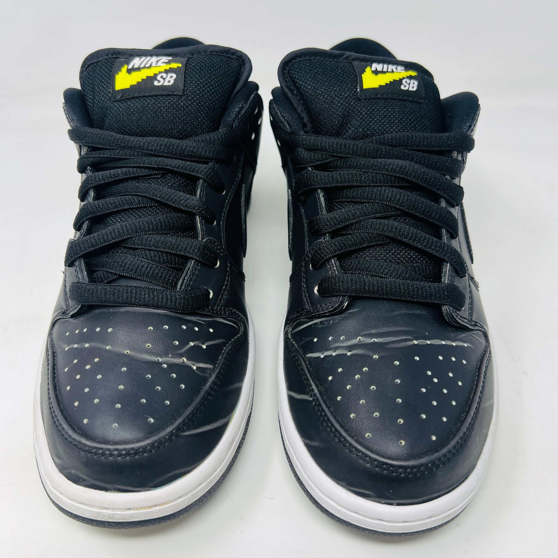 Nike SB Dunk Low Civilist sneakers, black with white soles and yellow tongue details, showcased on a white backdrop. They blend style and comfort effortlessly, making them a standout in 2020 sneaker collections.