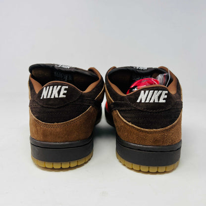 A pair of BRAND NEW Nike SB Dunk Low Bison sneakers featuring brown and red suede uppers, black laces, EXTRA LACES included, and a light brown sole. Positioned side by side on a white background, they promise to be 100% authentic and stylish.