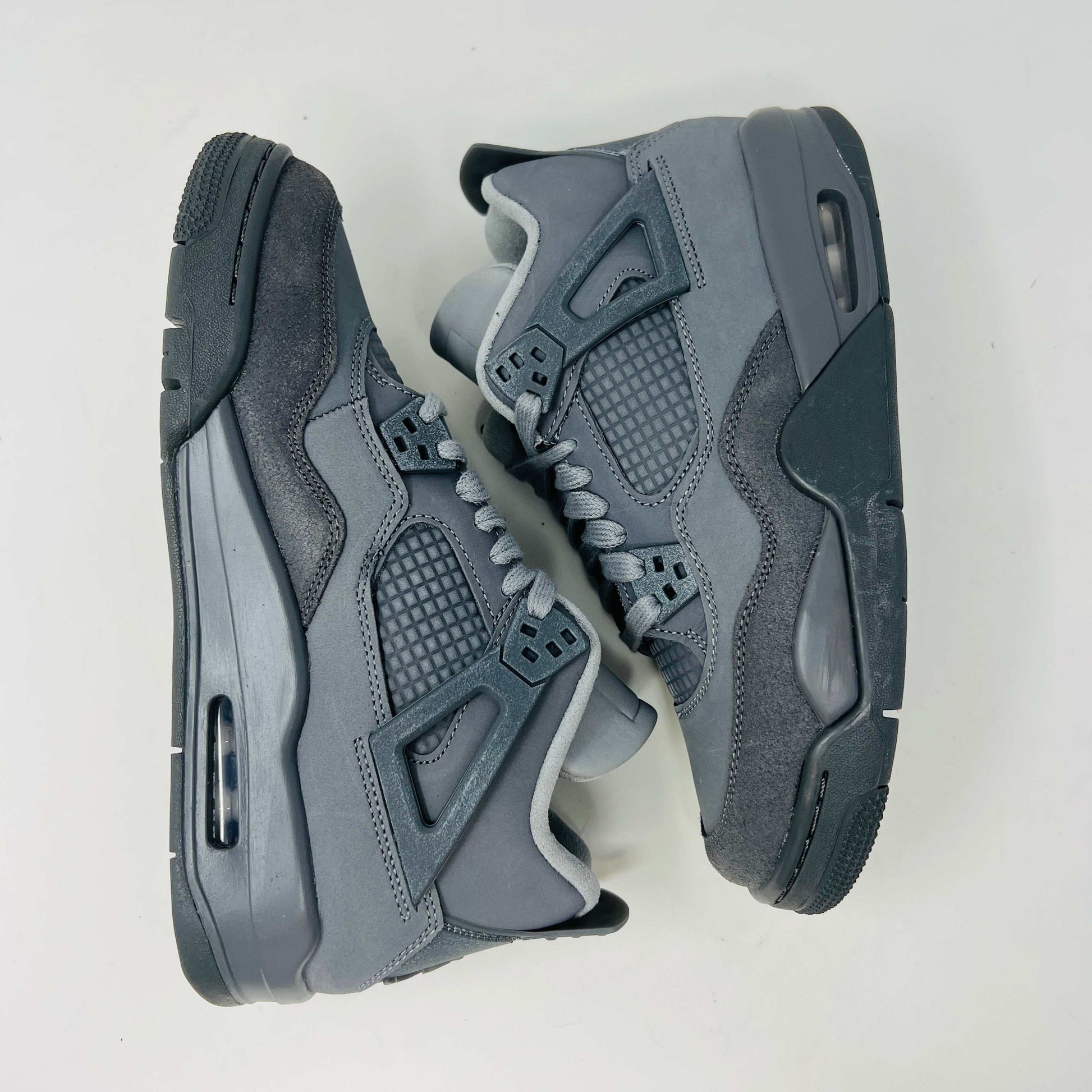 The Jordan 4 Retro SE Paris Olympics Wet Cement (GS), a brand-new gray sneaker, sits atop its pristine box. Featuring mesh and suede elements, it has a visible air unit in the midsole and a rubber outsole, poised to make an impression in 2024 against a plain white background.