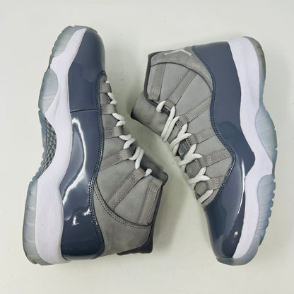 The Jordan 11 Retro Cool Grey (2021) sneaker, featuring clean gray and white uppers with glossy patent leather accents and white laces, is displayed on a gray Nike Air shoebox. The shoe is authentic in size 9.5, with the box in good condition.