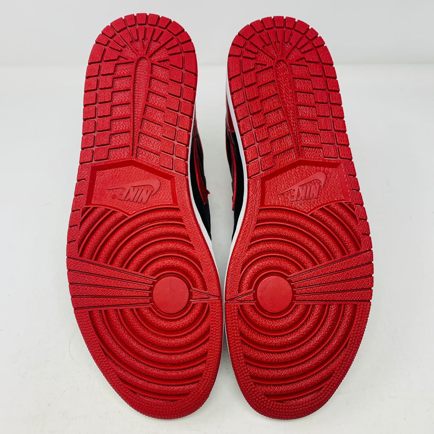 The Jordan 1 High Bred 2016 sneakers, by Jordan, are brand-new black and red high-tops with a white sole. Viewed from above, they showcase an unlaced look with a perforated design on the toe area.