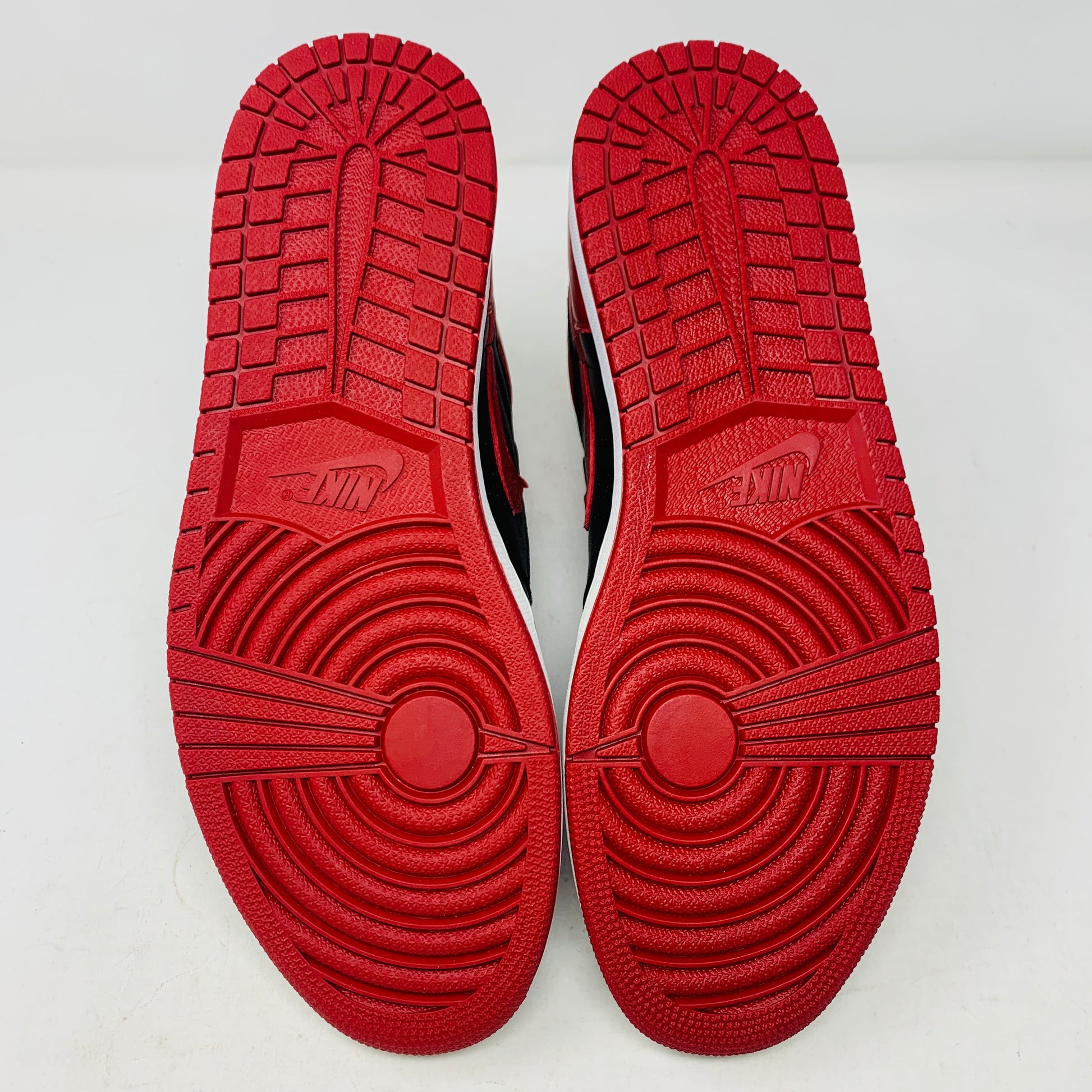 The Jordan 1 High Bred 2016 sneakers, by Jordan, are brand-new black and red high-tops with a white sole. Viewed from above, they showcase an unlaced look with a perforated design on the toe area.
